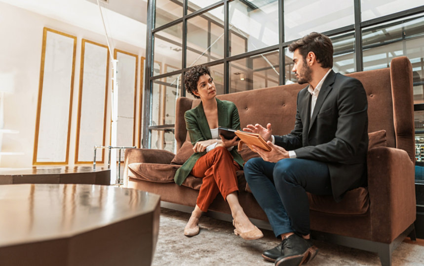 Two people talking in office touch down space.