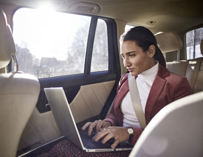 A woman sitting in a car using a laptop.