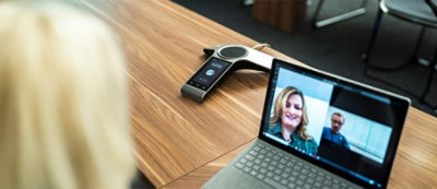 Un telefono per conferenze moderno con touchscreen e pulsanti posizionato su un tavolo di legno.