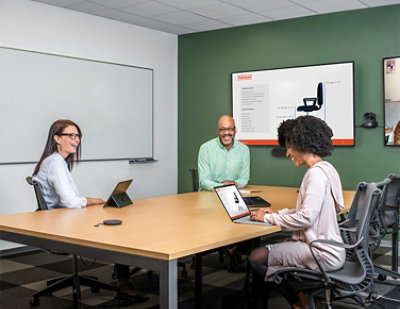 A group of people sitting at a table and working on there laptops
