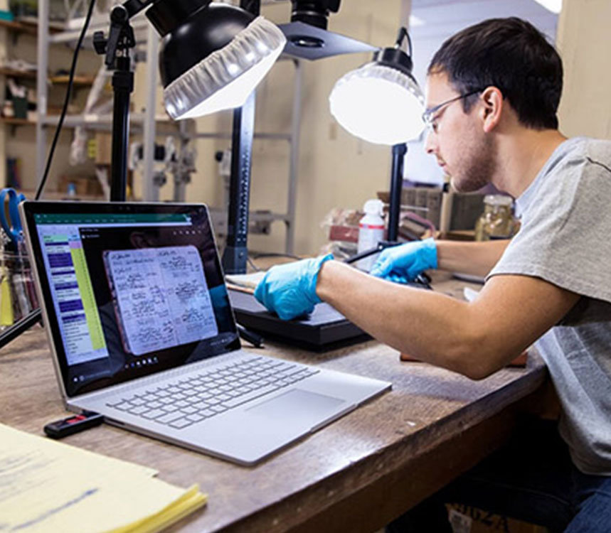 Een mannelijke werknemer werkt met opengeklapte laptop aan zijn bureau