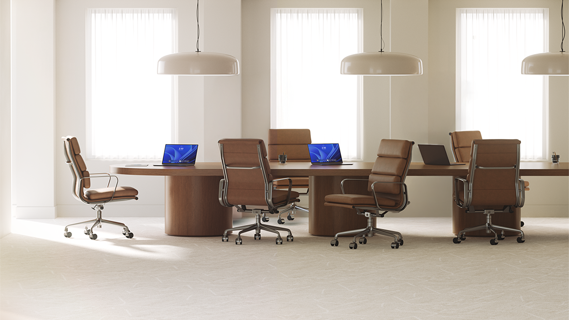 Three open laptops, with two displaying Windows blue bloom backgrounds, sit on a long wood conference room table surrounded by six brown leather office chairs