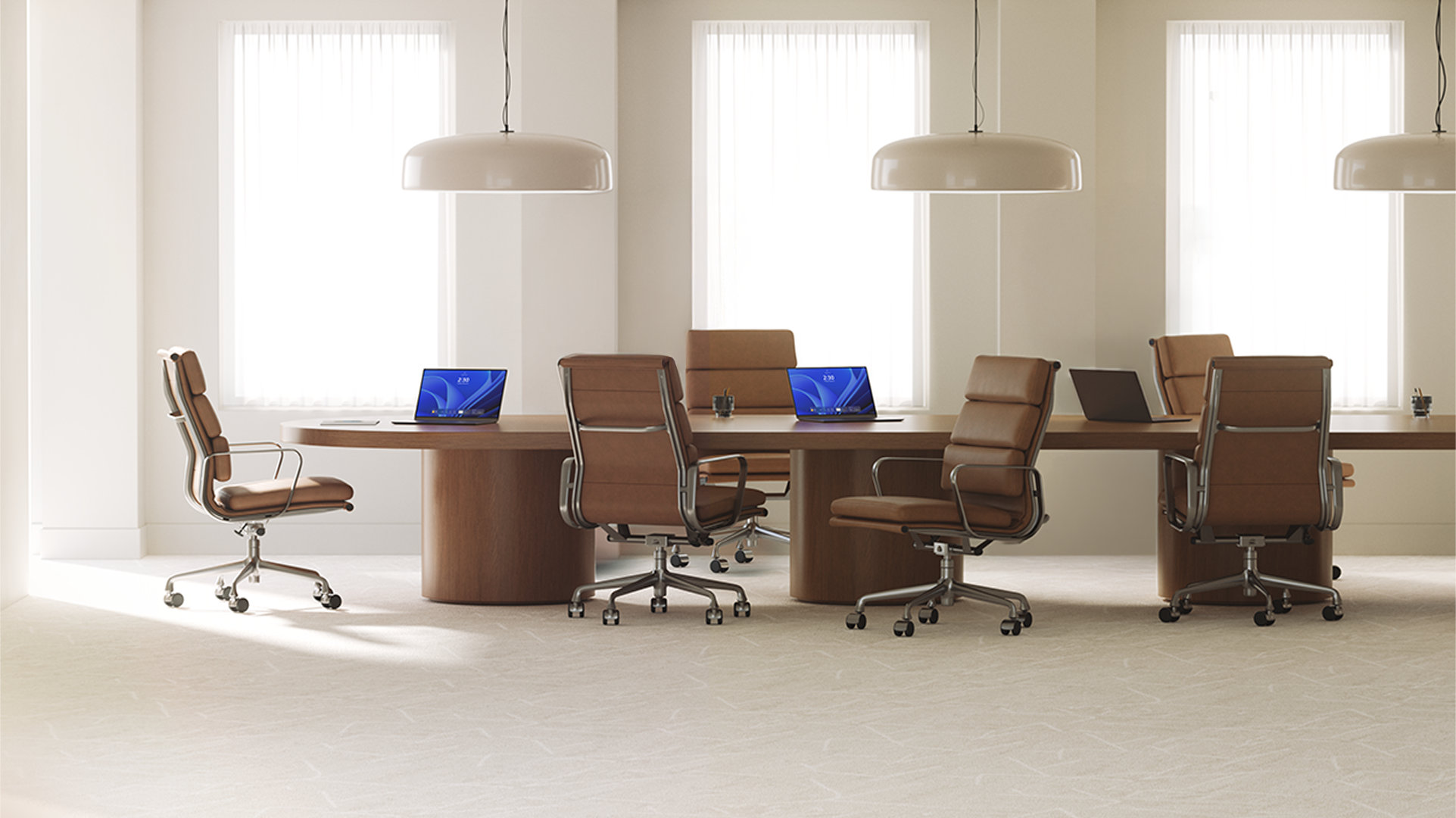 Three open laptops, with two displaying Windows blue bloom backgrounds, sit on a long wood conference room table surrounded by six brown leather office chairs
