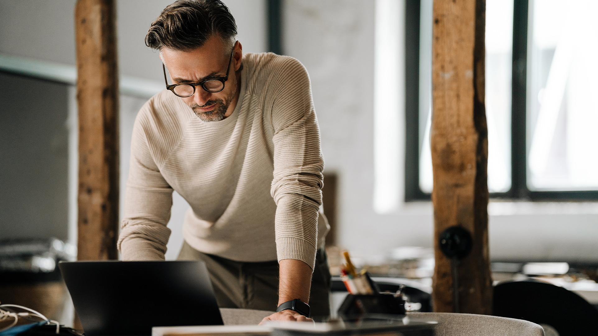 Office worker standing at a desk looking at an open Windows Pro PC in an open office setting