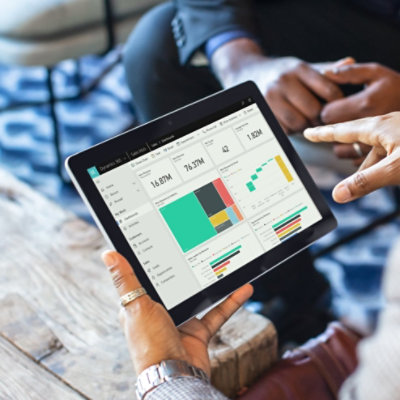 Mains tenant une tablette affichant des graphiques et diagrammes de données dans Dynamics 365
