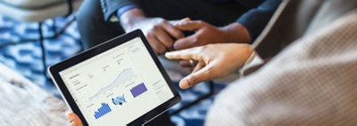 Hands holding a tablet displaying data in charts and graphs in Dynamics 365