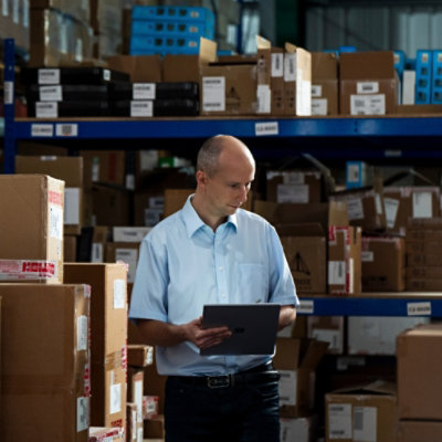 Personne tenant une tablette et travaillant dans un entrepôt rempli de boîtes