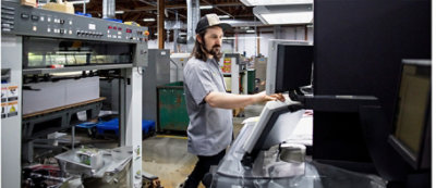 Un uomo che indossa un berretto aziona il pannello di controllo in un'industria con grandi