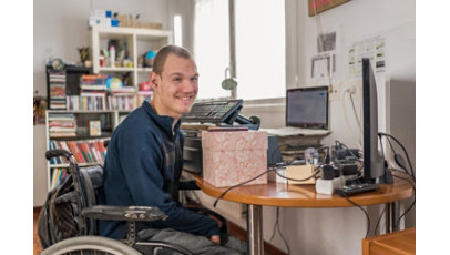 Man with disability in a wheelchair at his adapted worktable where he works from home.
