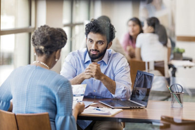 Customer reviews a bank brochure, while a bank employee explains the loan application process.