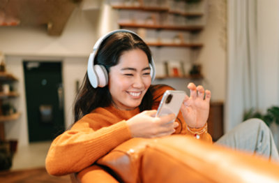 A person wearing headphones and looking at a phone.