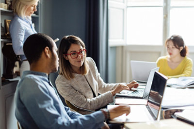 A women showing something on screen to a man in office.