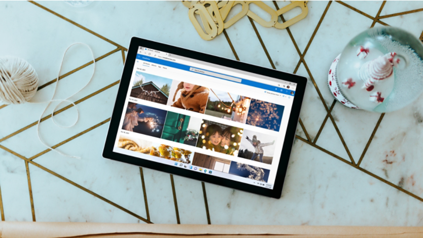 A Surface 2-in-1 PC with a OneDrive photo album on its screen