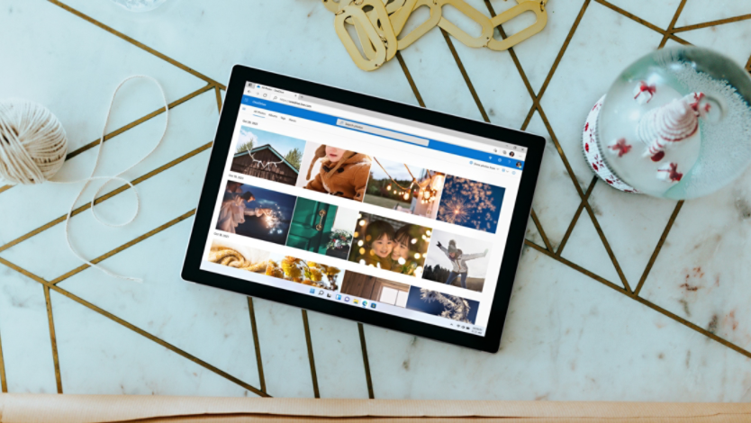 A Surface 2-in-1 PC with a OneDrive photo album on its screen