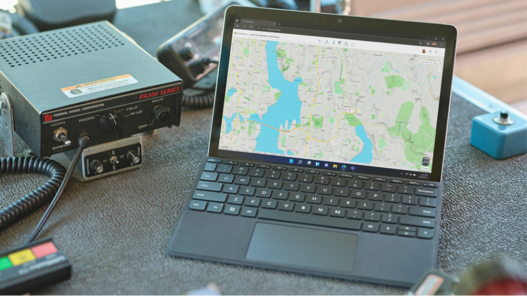 Zařízení Surface Go 3 vedle vysílačky pracovníka rychlého zásahu. Na obrazovce je mapa.