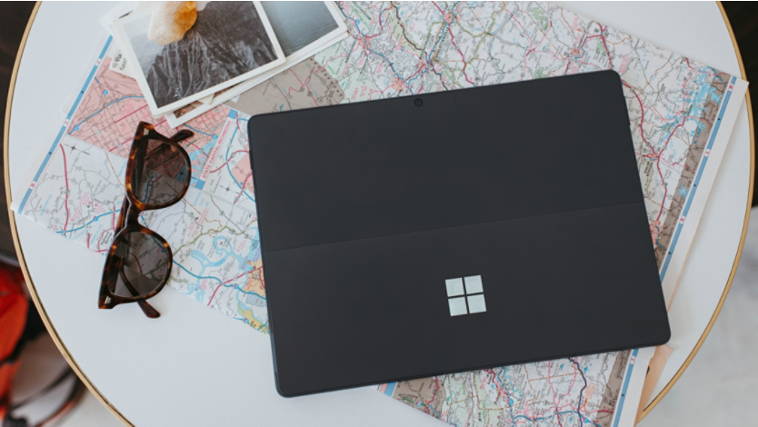 A Surface laptop with a map and other travel items