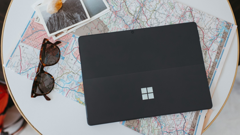 A Surface laptop with a map and other travel items