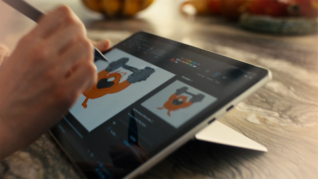 A closeup of a hand holding a Surface Slim Pen and drawing on the touchscreen of a Surface Pro