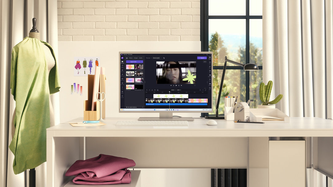 A computer monitor on a desk with writing utensils,  scissors, and small color swatches