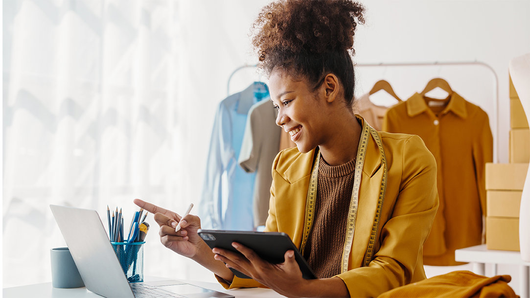 A fashion designer using Copilot AI while working on her laptop and tablet