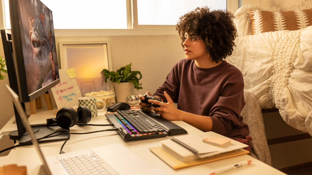 A female gaming using a controller and Windows 11 laptop PC at home