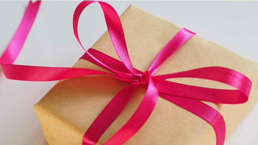 A gift wrapped in brown paper with a hot pink bow