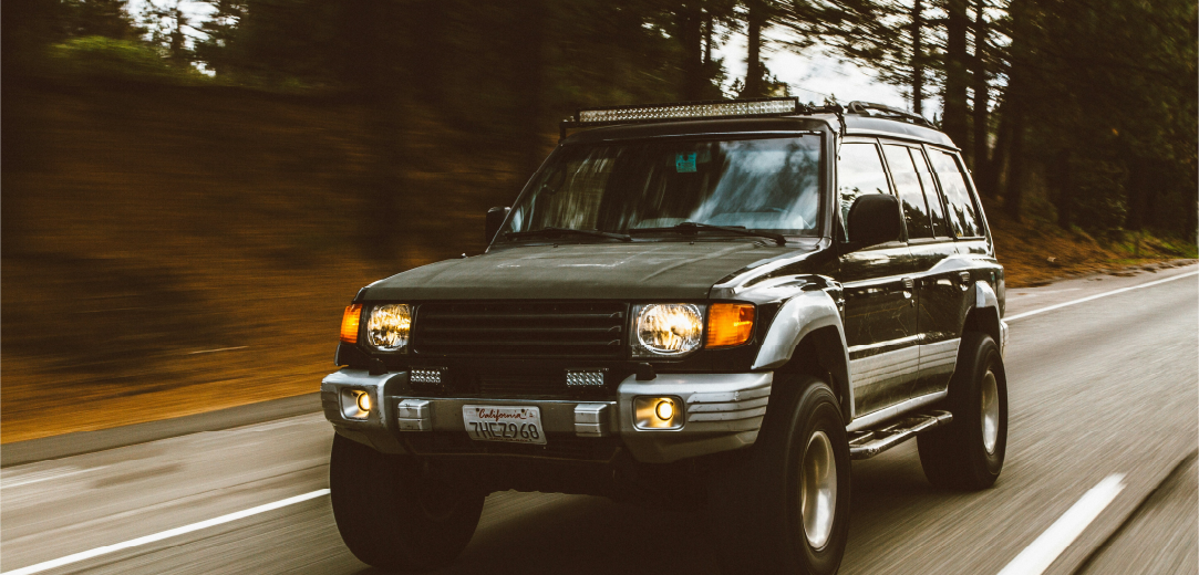 A green SUV driving on a road