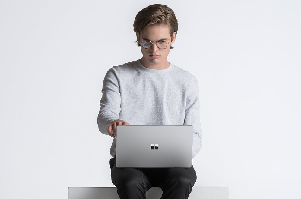 Seorang lelaki ditunjukkan sedang duduk dengan Surface Laptop 4 di atas ribanya