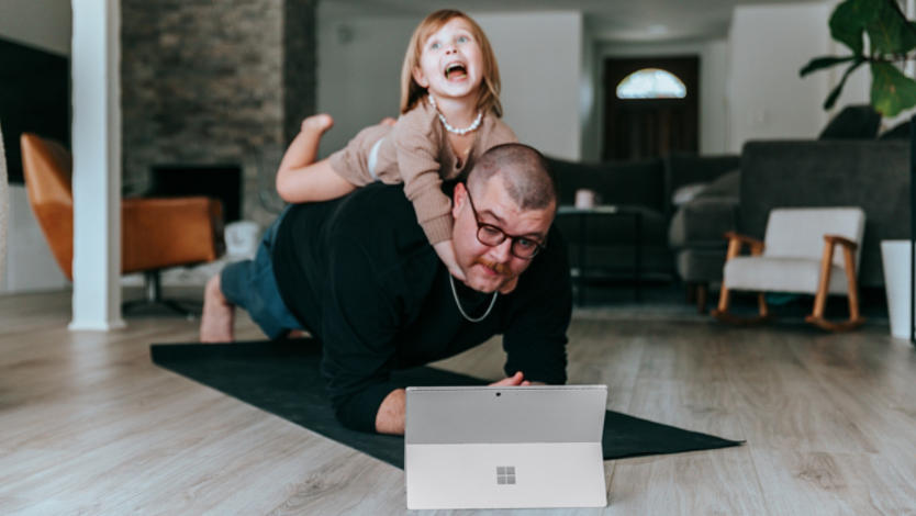 A man and a little girl playing with a Surface device
