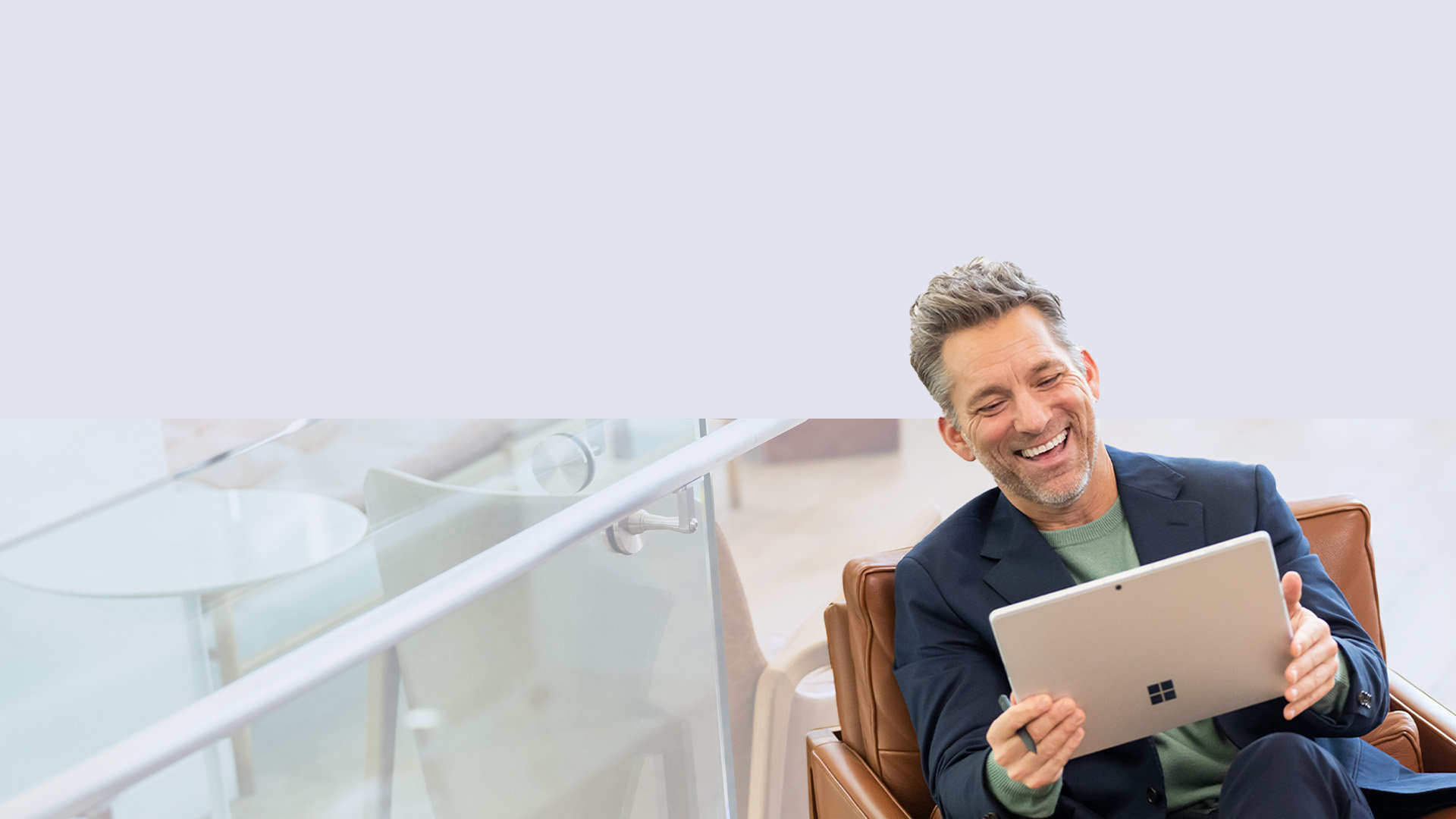 Muž sedící na pohovce drží v ruce pero Surface Slim Pen 2 a užívá si Surface Pro 9