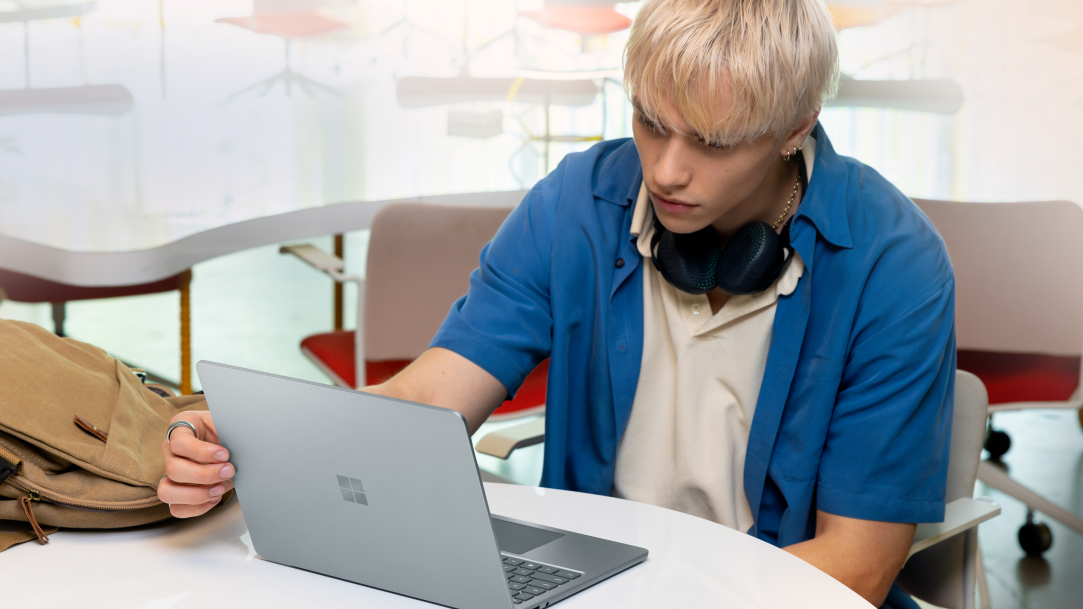 A man sitting at a table with a Surface Laptop Copilot+ PC