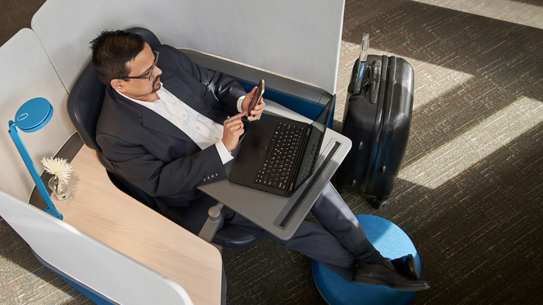 Un hombre sentado en una silla mientras trabaja con su portátil.