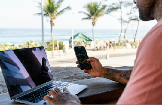 A man sitting outside at a resort holding his smartphone