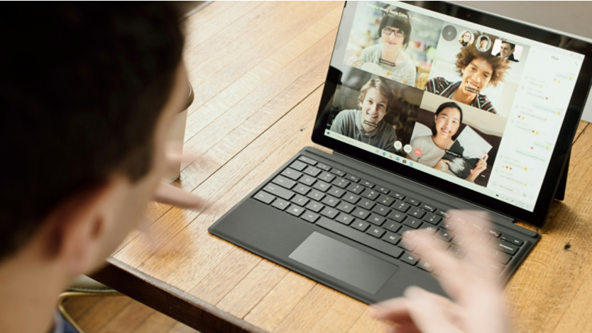 A man using a Surface laptop to meet virtually with friends