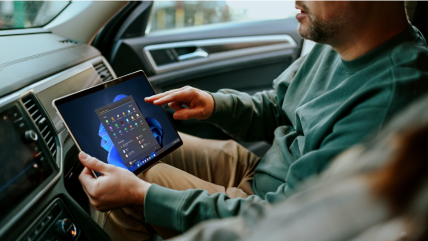 A man using a Surface tablet in the passenger seat of the car