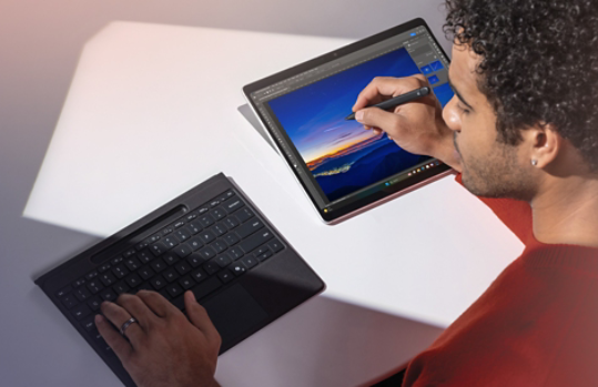 A man using a detached Surface Pro Flex Keyboard while writing on a Surface Pro 11ᵗʰ Edition with a Surface Slim Pen