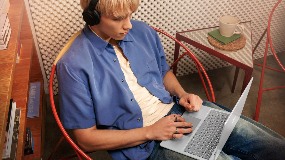 A man wearing headphones and using a Surface Laptop