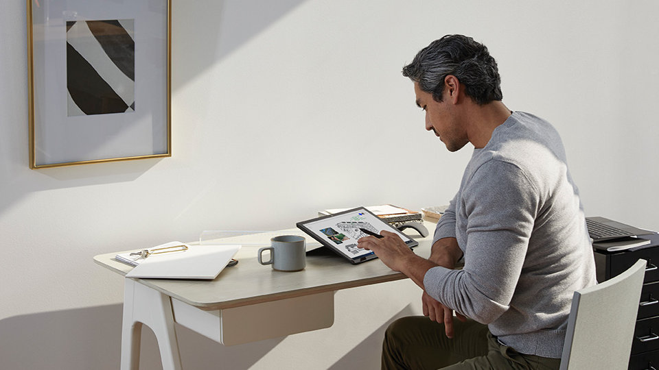 一名在家工作的男子在他的 Surface Pro 上使用 Surface 触控笔