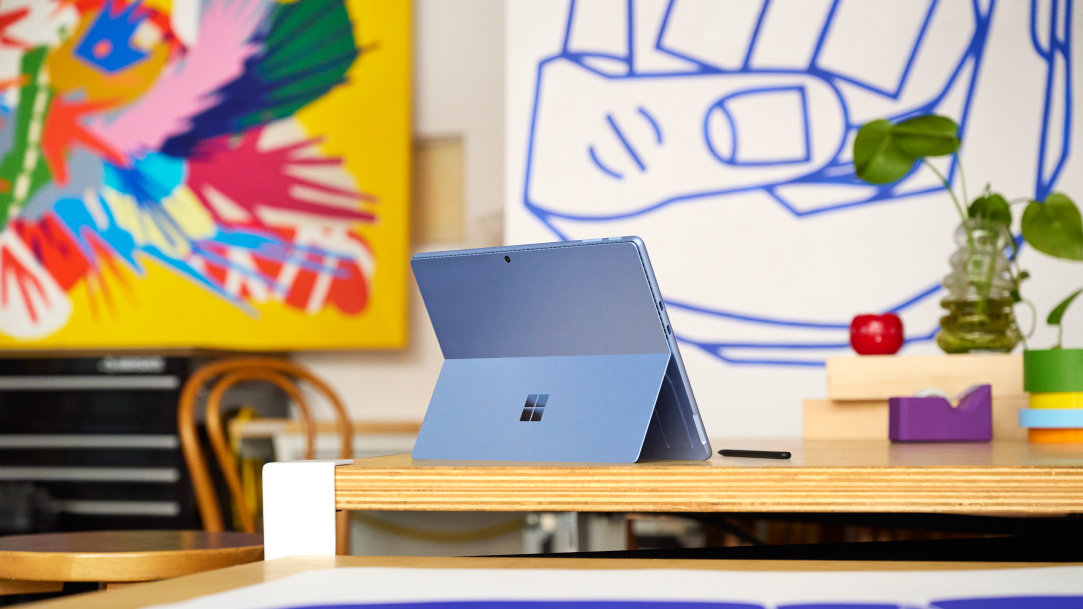 A blue Microsoft Surface laptop sitting on the table of an art studio