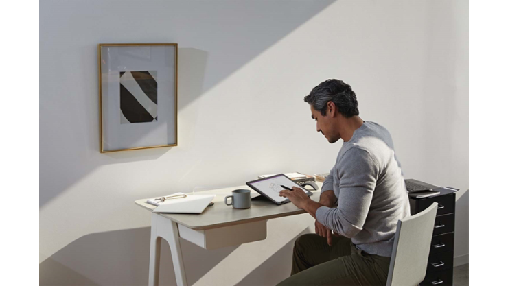 Mężczyzna pracujący w domowym biurze za pomocą pióra Surface i komputera Surface Pro