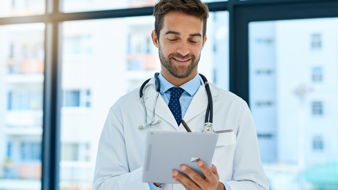 A medical professional in a hospital corridor and using a Surface Pro 2-in-1 in tablet mode