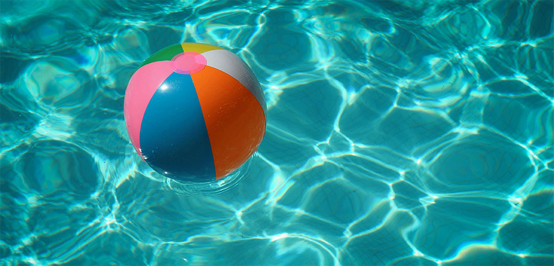 A multicolored beach ball floating on the water in a pool