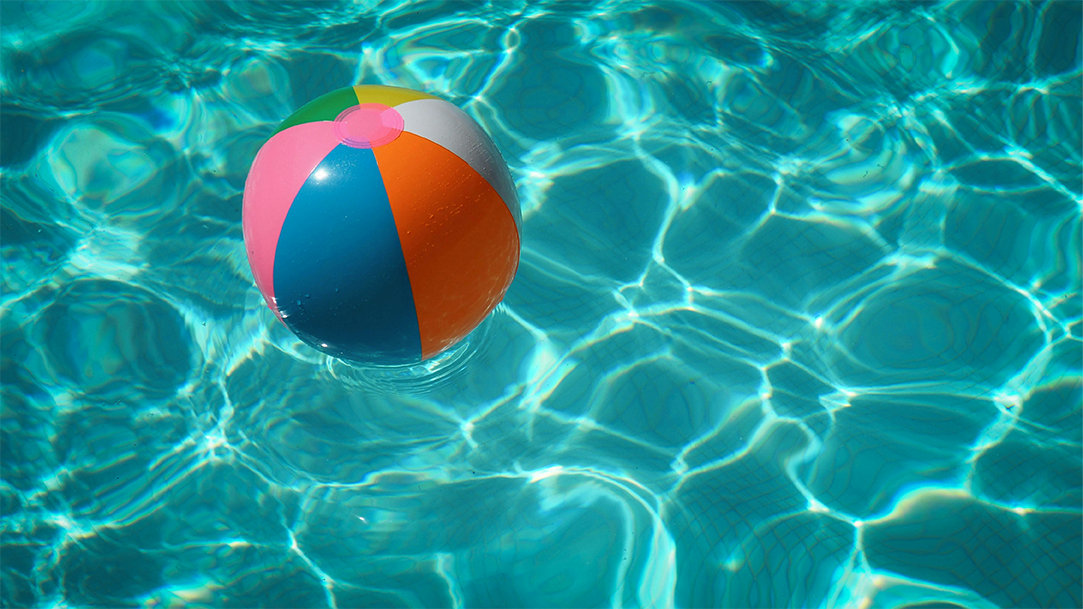 A multicolored beach ball floating on the water in a pool