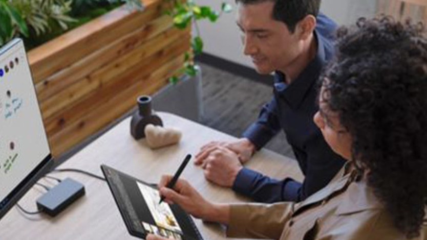 O persoană scrie în cerneală pe dispozitivul Surface Go 3, iar o altă persoană o observă