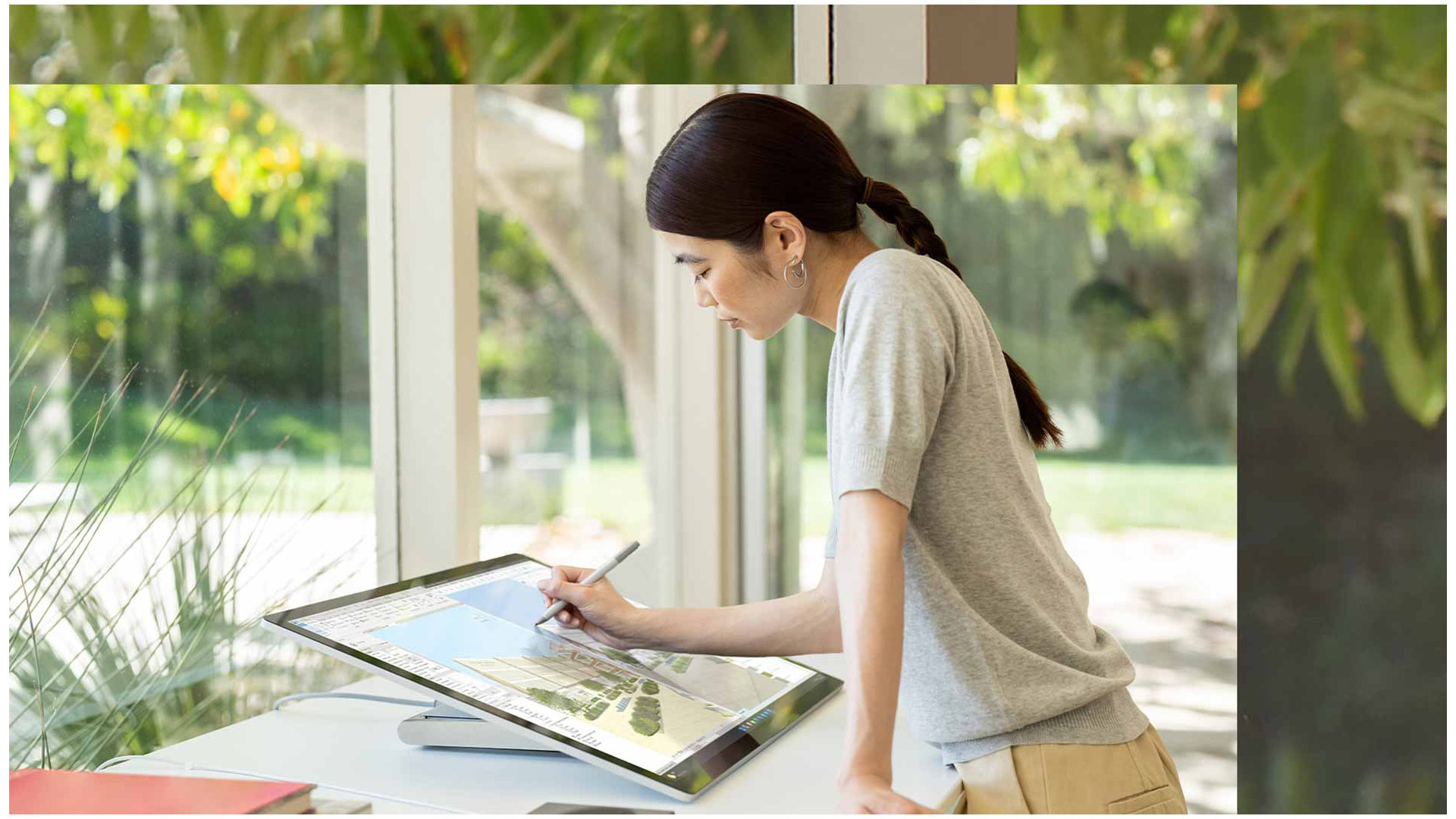 Iemand schrijft of tekent met Surface Pen op het scherm van een Surface Studio 2+ in een thuiskantoor