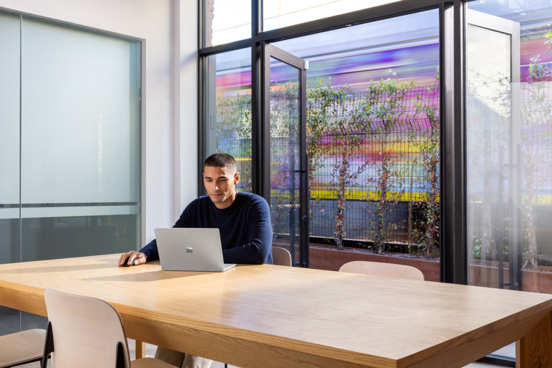 A person using a Surface laptop and wireless mouse