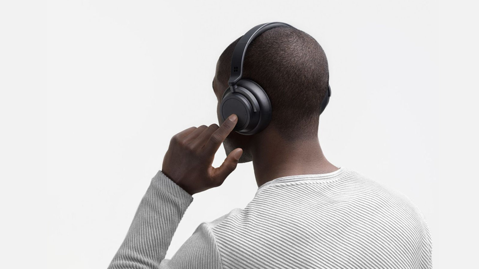 A person wears Surface Headphones 2+ and is shown using touch controls