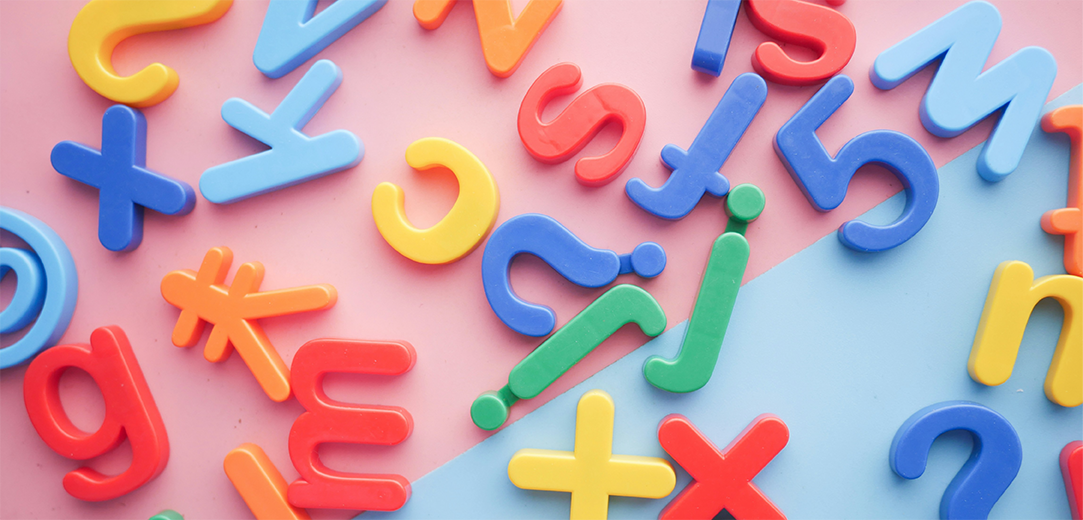 A pile of plastic letters and numbers from different languages on a pink and blue background