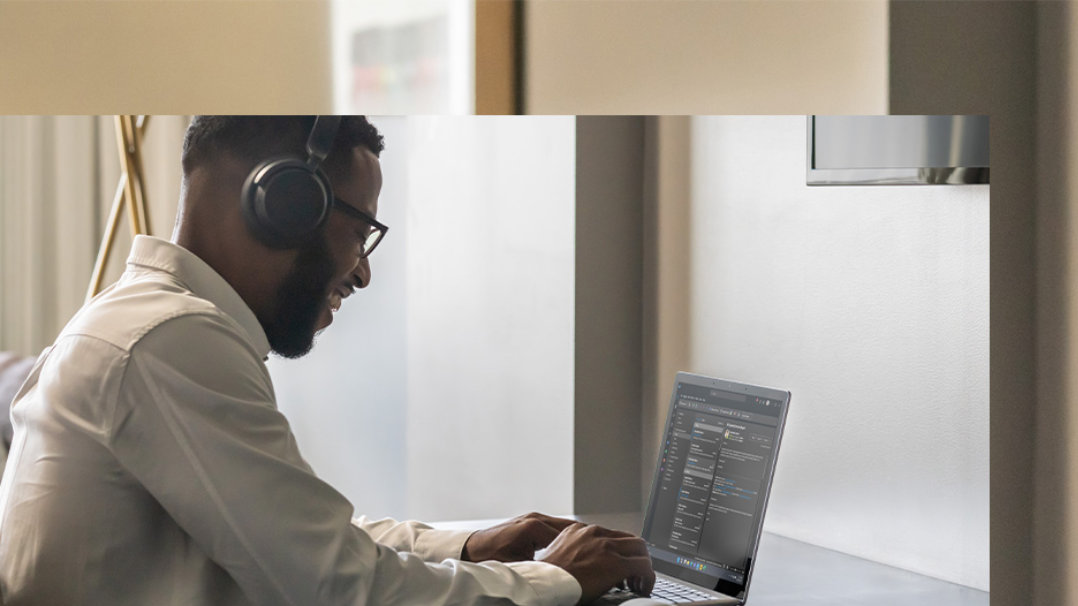 A side profile of a person working on Surface Laptop 5 at home