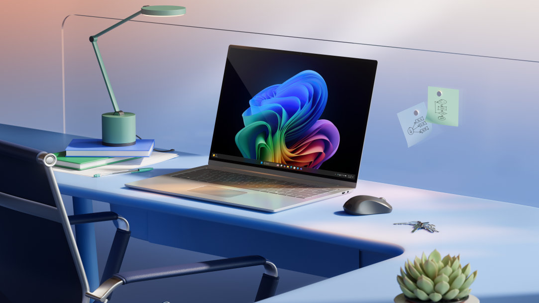 A silver device on a desk showing Copilot+ PC bloom on the screen